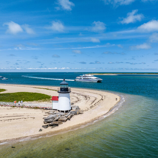 A lighthouse on a beach next to a boat.