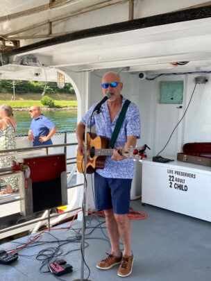 A man singing on a boat with a guitar.