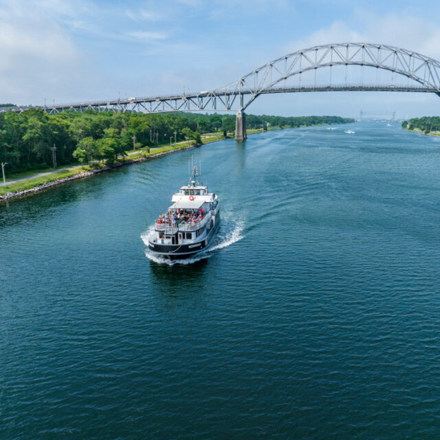 An aerial view of a boat traveling under a bridge.