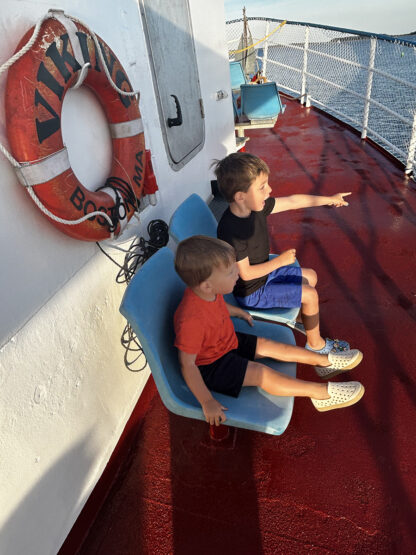 two young boys on a boat with one pointing